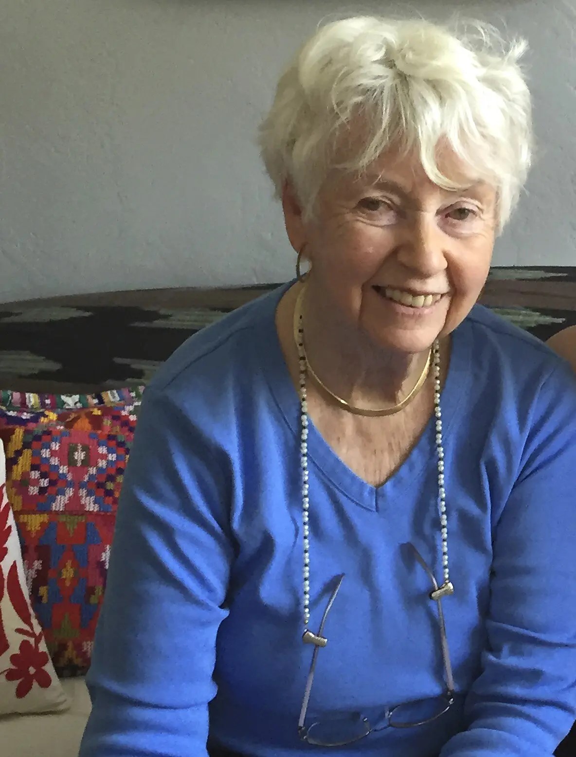 Author Eve Bunting. Photo shows an older white woman with short white hair, wearing a long sleeved blue shirt and a long chain around her neck.