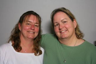 Two white women smiling next to each other against white backdrop